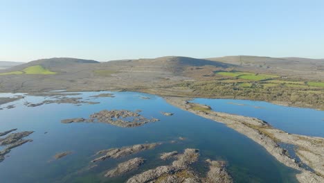 Panoramic-aerial-establishes-blue-sky-reflecting-in-flood-waters-on-Burren-Ireland-with-stunning-rock-formations