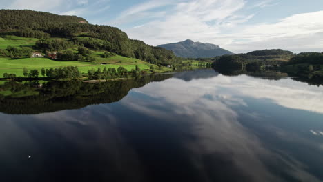 Aerial-shot,-panning-across-the-green-shoreline-of-a-lake-in-Norway