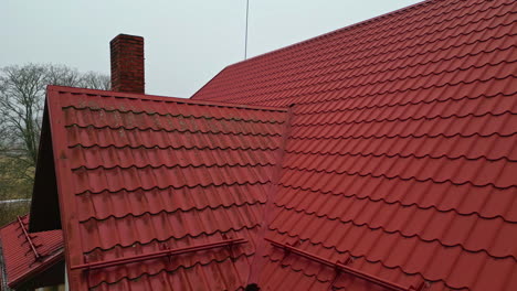 House-with-red-tiles-roof-and-smoke-chimney,-aerial-rural-location