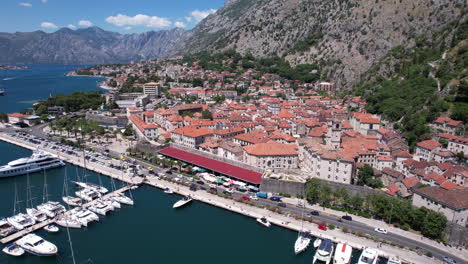 Casco-Antiguo-De-Kotor,-Montenegro,-Vista-Aérea-Del-Fuerte-Medieval,-Tráfico-Por-El-Puerto-Y-La-Bahía-En-Un-Día-Soleado,-Disparo-De-Drone