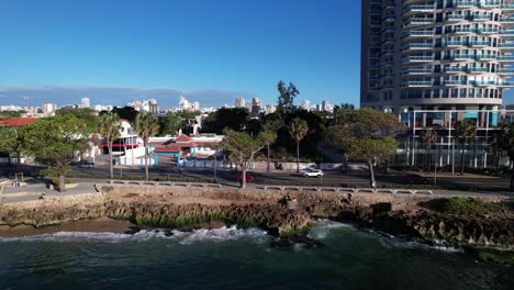 Luftbildverfolgung-Eines-Roten-Autos-An-Der-Strandpromenade-Malecon,-Santo-Domingo,-Dominikanische-Republik