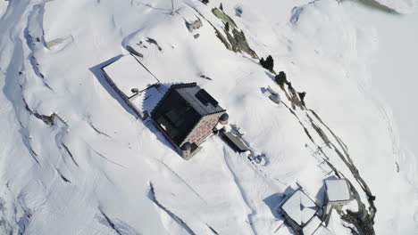 Aerial-of-a-house-surrounded-by-snow-and-mountains