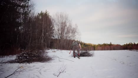 Back-View-Of-Man-Walking-On-Snow-At-The-Farm-To-Pull-Out-Cut-Leafless-Tree-In-Winter