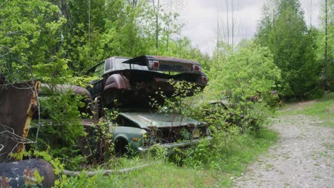 Pull-away-shot-of-smashed-cars-stacked-on-top-of-each-other-then-showcasing-an-abandoned-dirt-road