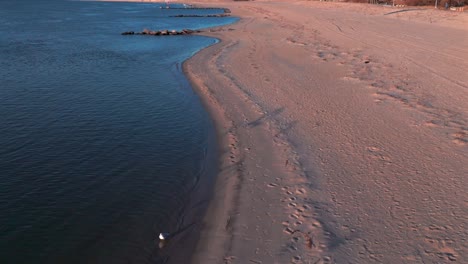 A-low-angle-view-of-the-empty-beach-on-Reynolds-Channel-in-Atlantic-Beach,-NY-during-sunrise