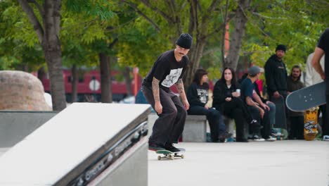 Ein-Teenager-In-Schwarz,-Der-Vor-Seinen-Freunden-Angibt,-Macht-Auf-Seinem-Skateboard-Einen-Trick-In-Einem-Skatepark-Und-Verliert-Dabei-Seine-Kontrolle