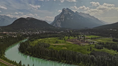 Banff-Ab-Canada-Vista-Aérea-V47-Pintoresco-Paisaje-Del-Río-Bow-Alimentado-Por-Glaciares,-Establos-En-Prados,-Pintoresca-Ciudad-Al-Pie-De-Las-Colinas,-Valle-Boscoso-Y-Cadenas-Montañosas-Rundle---Filmado-Con-Mavic-3-Pro-Cine---Julio-De-2023