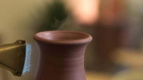 Close-up-rotating-clay-vase-on-pottery-wheel-glazed-with-propane-torch-flame