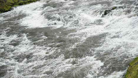 Toma-Panorámica-Lenta-De-Un-Enorme-Y-Ancho-Río-Rápido-Que-Fluye-Y-Brota-De-Espuma-Blanca