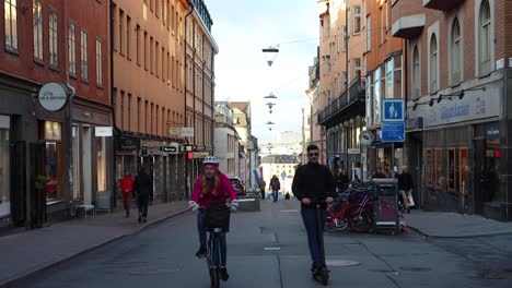 People-walk-and-ride-bikes-and-scooters-on-street-in-Stockholm,-static