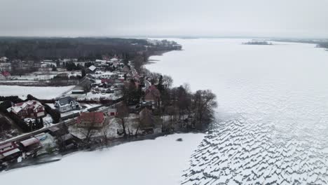 Drohne-Erstellt-Überblick-über-Schneebedeckten-See-Und-Ländliche-Stadt-In-Der-Nähe-Von-Suwalki-Lücke-Masuren-Polen-Im-Winter