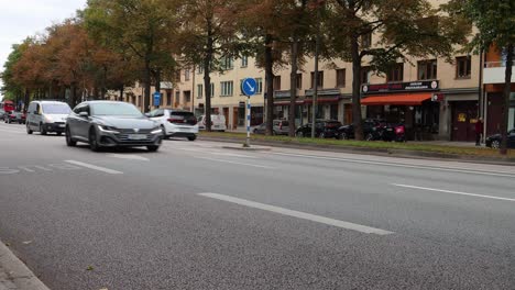 Ambulance-and-car-traffic-on-street-in-autumn-Stockholm,-static-shot