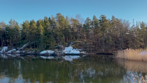 Ruhige-Winterlandschaft-Einer-Schneebedeckten-Insel-Im-Stockholmer-Archipel,-Die-Sich-Im-Ruhigen-Wasser-Spiegelt
