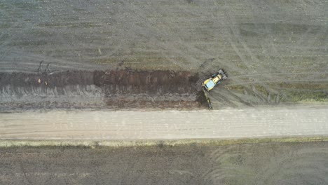 Aerial-top-down-view-of-excavator-machinery-dig-drainage-trench-near-road