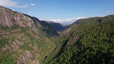 Aerial-shot,-descending-into-a-deep-valley-with-dense-forest-and-steep-cliffs-on-it's-sides