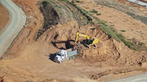 Yarrawonga,-Victoria,-Australia---8-March-2024:-Tip-truck-backing-into-soil-stockpile-at-Silverwoods-Estate-and-excavator-loading