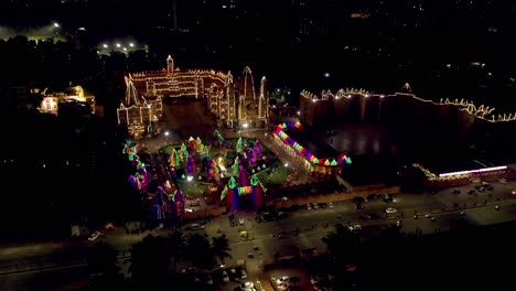 AERIAL-DRONE-VIEW-DRONE-CAMERA-IS-GOING-BACKWARDS-WHERE-THE-TEMPLE-LOOKING-GLASS-IS-LOOKING-VERY-BEAUTIFUL-AND-GORGEOUS-WITH-THE-LIGHTING-WHERE-A-LOT-OF-BUILDINGS-AND-PARTY-PLOTS-ARE-SHOWING-AROUND