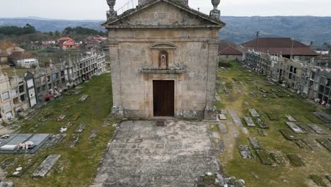Fast-aerial-pullback-from-carved-figurine-in-apse-of-old-mossy-church-building-surrounded-by-cemetery-of-Santa-Maria-de-Freas-in-Punxin-Ourense-Galicia-Spain