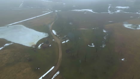 Luftaufnahmen-Von-Bauernhäusern-Im-Hinterland-Inmitten-Verstreuter-Bäume-In-Einer-Graslandschaft,-Nebliges-Klima-Im-Winter