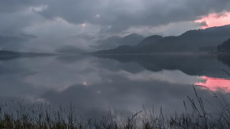 Niedrige-Wolken-Kriechen-über-Den-Dramatischen-Sonnenuntergangshimmel-über-Dem-Noch-Spiegelglatten-See