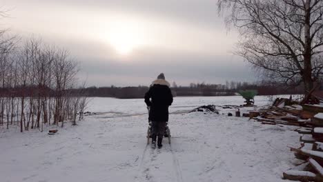 Single-mother-push-baby-carriage-on-snowy-ground,-sun-through-clouds