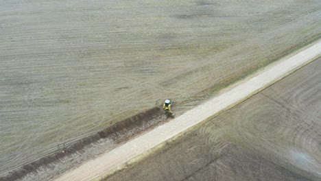 Aerial-view-of-tractor-excavator-on-field-dig-drainage-ditch-near-gravel-road