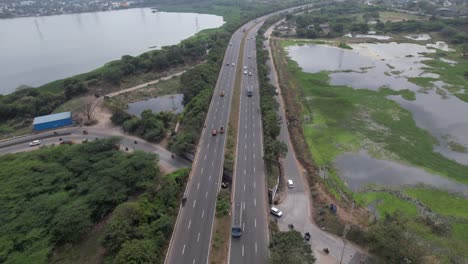 Aerial-Drone-Shot-of-Highway-Near-A-Lake-Filled-with-Rich-Drinking-Water