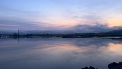 Time-Lapse-of-Lake-with-Clouds-reflections-shrouded-in-fog-at-sunrise