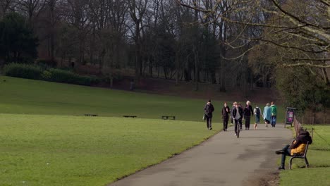 People-walking-dogs,-cyclists-within-a-sunny-and-calm-Queens-Park,-South-Side-of-Glasgow