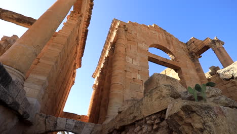 Sunlit-ancient-Roman-ruins-of-Sbeitla-against-a-clear-blue-sky-in-Tunisia,-low-angle-view