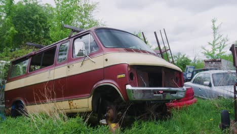 Halbumlaufende-Aufnahme-Eines-Verlassenen-Lieferwagens-Ohne-Scheinwerfer-Oder-Reifen,-Der-Neben-Einigen-Anderen-Autos-In-Einem-überwucherten-Wald-Steht