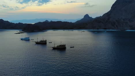 three-tourist-ships-anchored-off-the-coast-of-Padar-Island-in-Komodo-National-Park,-Indonesia,-during-the-evening,-showcasing-the-wild-beauty-of-the-surroundings
