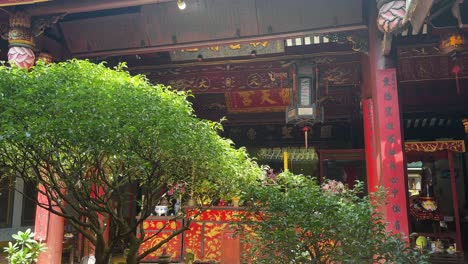 Small-Asian-trees-in-red-courtyard-of-Guan-Di-Buddhist-Temple,-Hoi-An,-Vietnam