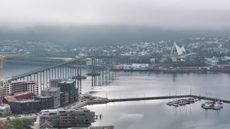 Drohnenaufnahme-Des-Hafens-Von-Tromsø,-Der-Meerenge-Und-Der-Gebäude-In-Der-Nebligen-Skyline,-60 fps