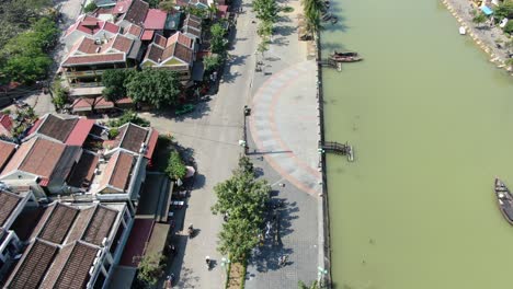 Vista-Aérea-De-Drones-En-Vietnam-Volando-Sobre-Hoi,-Un-Canal-Fluvial-De-Color-Marrón-En-La-Ciudad,-Pequeñas-Casas-De-Ladrillo-Y-Barcos-De-Madera-En-Un-Día-Soleado