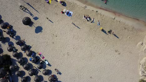 Overhead-drone-shot-of-Calla-Mondrago-beach-resort,-showing-a-number-of-beachgoers-who-are-sunbathing-and-swimming-in-the-idyllic-waters-of-the-Mediterranean-Sea