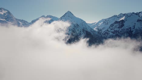 Video-Einer-Drohne,-Die-Durch-Die-Wolken-Auf-Eine-Schneebedeckte-Bergkette-Zufliegt