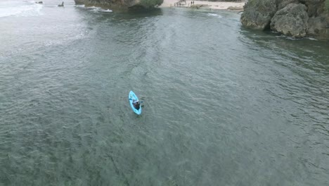 Orbit-drone-shot-of-a-man-kayak-on-the-beach-in-tropical-island