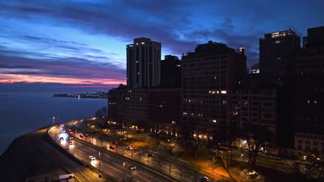 Aerial-view-rising-in-front-of-the-Lake-Shore-drive,-dusk-on-the-coast-of-Chicago