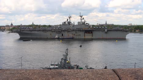 Kleines-Boot-Fährt-In-Schweden-Am-Riesigen-Amerikanischen-Schlachtschiff-USS-Kearsarge-Vorbei