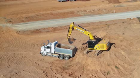 Yarrawonga,-Victoria,-Australia---8-March-2024:-Excavator-loading-soil-into-a-tip-truck-and-gently-breaking-up-large-pieces-at-a-new-building-site-at-Silverwoods-Estate-in-Yarrawonga