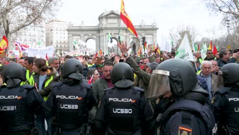 A-panning-shot-of-police-officers-intervene-as-Spanish-farmers-and-agricultural-unions-gather-at-Plaza-de-la-Independencia-to-protest-against-unfair-competition,-agricultural-and-government-policies