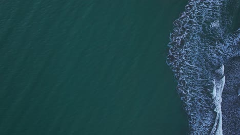 Drone-shot-looking-straight-down-on-waves-crashing-up-on-the-beach-in-California