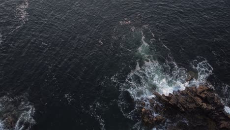 aerial-top-down-drone-of-ocean-water-waves-crashing-in-to-rocks