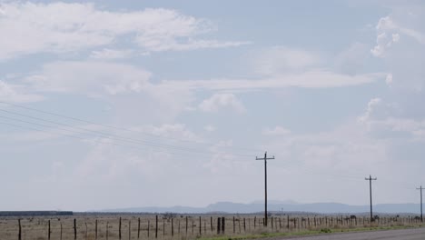 Train-passing-in-the-distance-with-telephone-poles-in-the-foreground,-surrounded-by-endless-Texas-skies