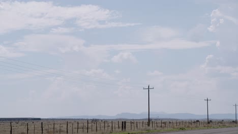 Tren-Pasando-A-Lo-Lejos-Con-Postes-Telefónicos-En-Primer-Plano,-Rodeado-Por-Infinitos-Cielos-De-Texas