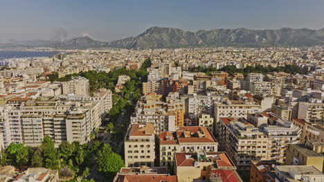 Palermo-Italy-Aerial-v12-fly-along-Via-della-Liberta-capturing-leafy-street,-cityscape-across-residential-and-downtown-areas,-city-park-and-mountain-on-the-skyline---Shot-with-Mavic-3-Cine---May-2023