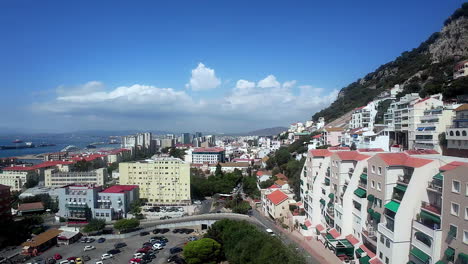 Luftdrohne-Fliegt-Um-Küstenstadt-Vintage-Resorthäuser,-Alboran-Meer,-Gibraltar-Stadtbild-Mit-Sonniger-Skyline,-Autos-Parken-Rund-Um-Lebhafte-Mediterrane-Strandstadt
