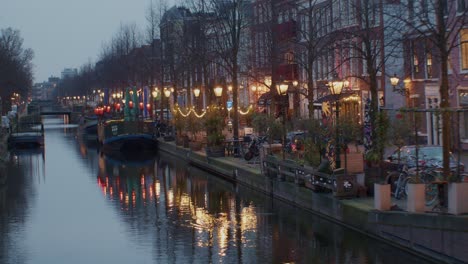 Un-Hermoso-Paisaje-Cinematográfico-Con-Vistas-Nocturnas-De-La-Ciudad-De-La-Haya-O-Den-Haag-Con-Canal,-Agua-Y-Barco-En-El-Auténtico-Estilo-De-Arquitectura-Tradicional-Europea-De-Los-Países-Bajos-Holandeses.