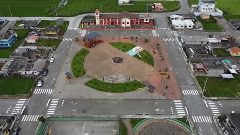 Clip-Cinematográfico-De-Drones-Volando-Sobre-Un-Parque-Hacia-Una-Iglesia-Roja-En-Un-Pueblo-De-Chaupi,-Ecuador